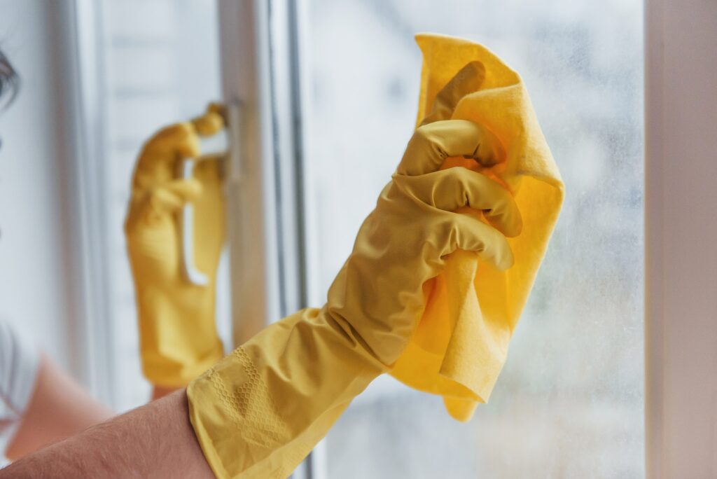Housewife in yellow uniform cleaning windows. House renovation conception
